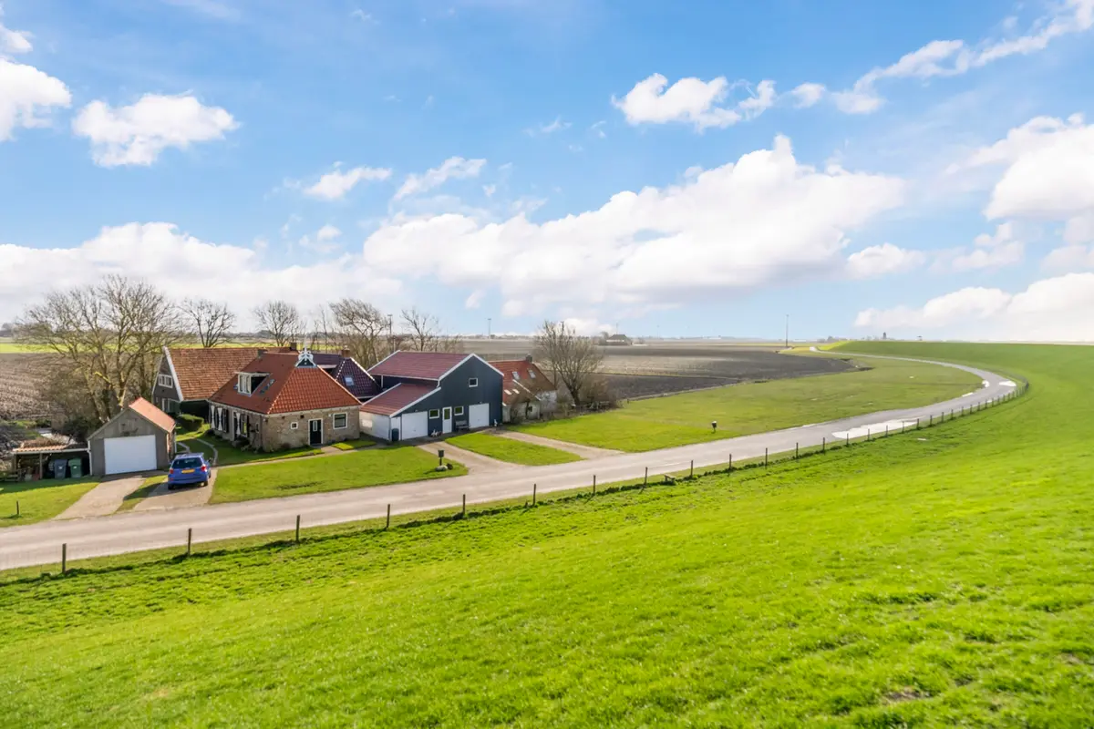 Woningen achter de dijk in het Friese landschap