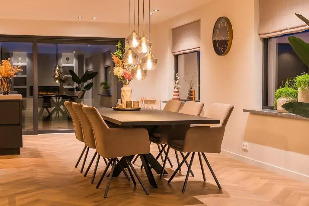 Eettafel onder hanglampen in een warm verlichte woonkamer