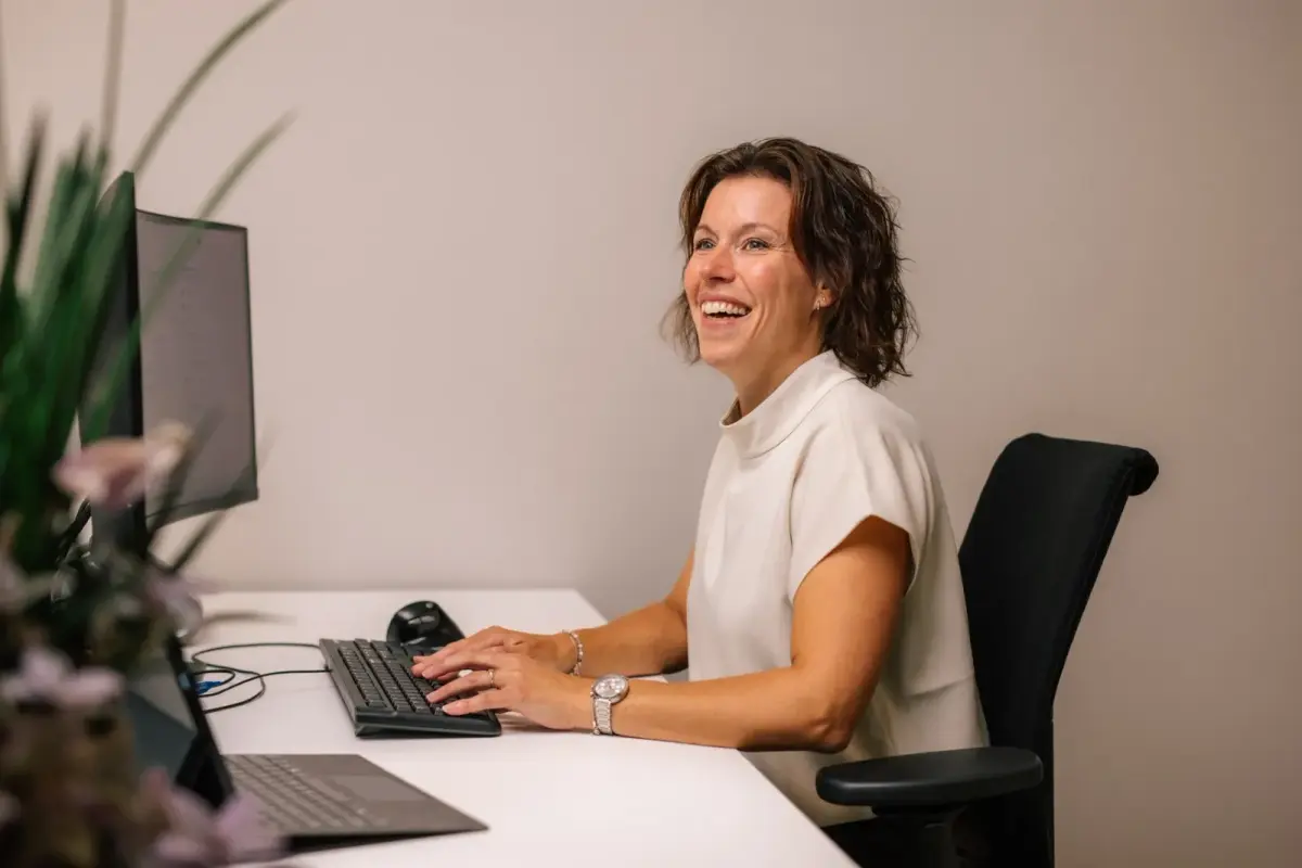 Medewerker van Makelaardij Germeraad lacht aan haar bureau achter de computer