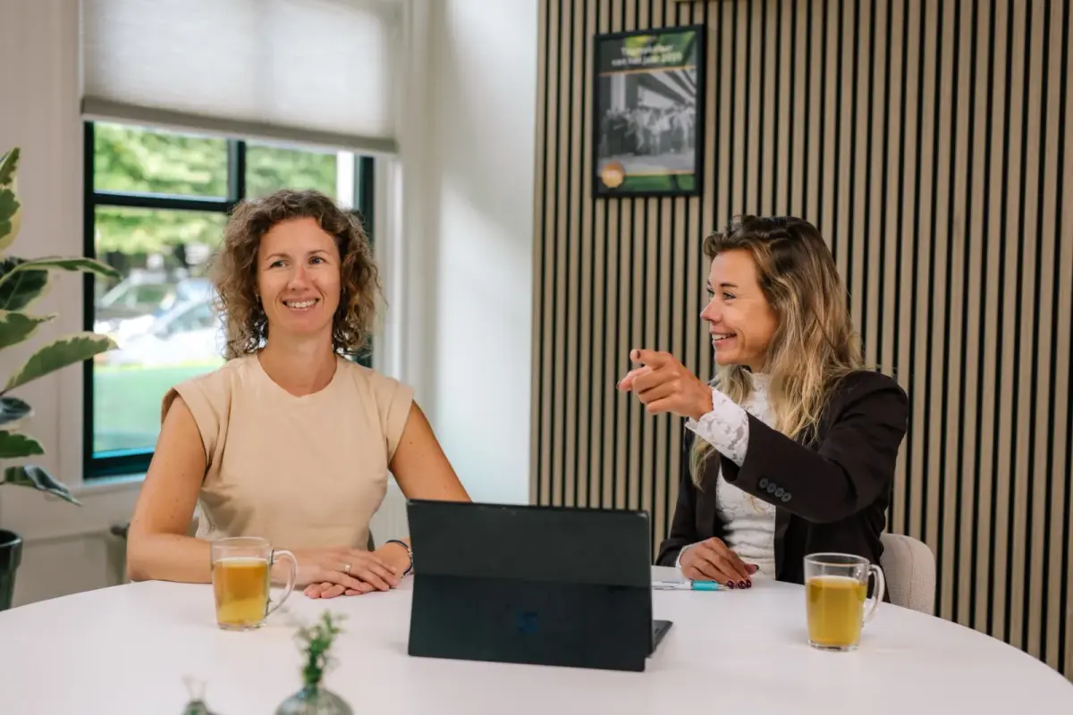 Twee collega’s van Makelaardij Germeraad in gesprek aan een ronde tafel met een laptop